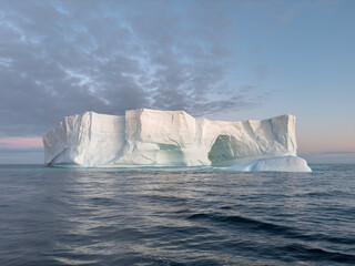 A huge high breakaway glacier drifts in the southern ocean off the coast of Antarctica at sunset,...