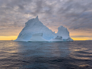 A huge high breakaway glacier drifts in the southern ocean off the coast of Antarctica at sunset,...