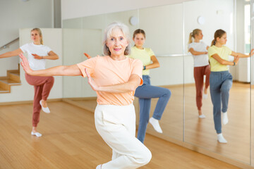 Fototapeta premium Aged lady dancing with her family in studio during group aerobic training.