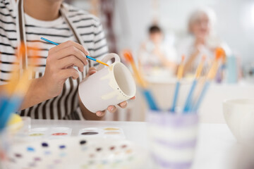 Closeup of hands of talented female artisan creating own unique ceramic items in pottery workshop,...