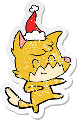 distressed sticker cartoon of a friendly fox wearing santa hat