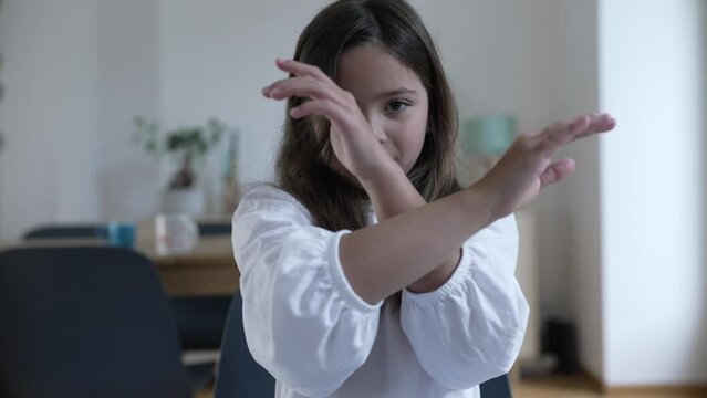 One small girl waving NO with finger stating clear rejection, X with arms looking at camera