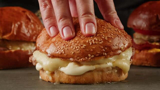 American fat smash burger with fresh tomatoes, acon slices, fried onion and cheese on grill close-up macro. Beef or pork cutlet smashing by burger press. The chef in kitchen of the restaurant making
