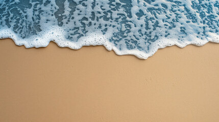 Gentle blue toxic looking wave with frothy foam over golden sand.