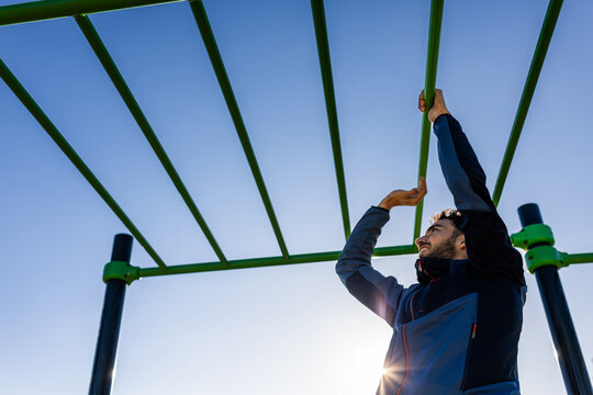 Person doing sports on exercise bars, pull up bar