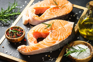 Salmon fish fresh steaks on cutting board at black background. Macro.