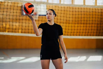 Fotobehang A teenage volleyball player with a ball on court. © Zamrznuti tonovi