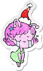distressed sticker cartoon of a crying alien girl wearing santa hat