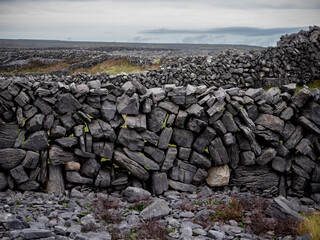 Traditional dry stone fence by a field. Aran islands, county Galway, Ireland. Popular tourist area with stunning nature scenery and endless stone fences. Old craft and simple construction material.