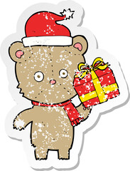 retro distressed sticker of a cartoon christmas teddy bear with present