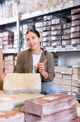 Young woman carefully chooses briquettes with white clay in a specialized store
