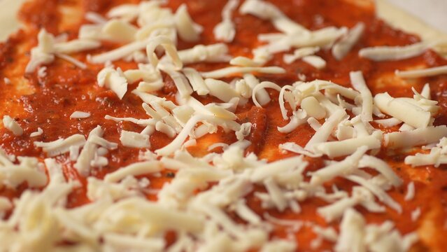 Adding Cheese to Tomato Sauce Pizza Base. Close-up, shallow dof. - Powered by Adobe