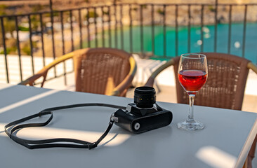 Retro camera and glass of red wine on the table.