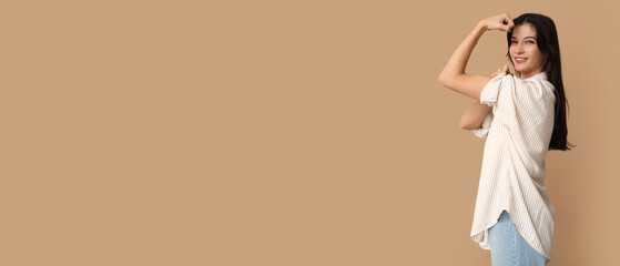 Young woman flexing muscles on beige background with space for text. Feminism concept