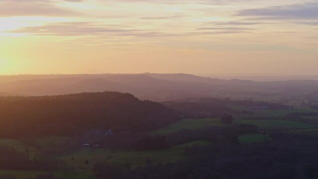 Tracking telephoto aerial shot of rural British landscape at sunset golden hour