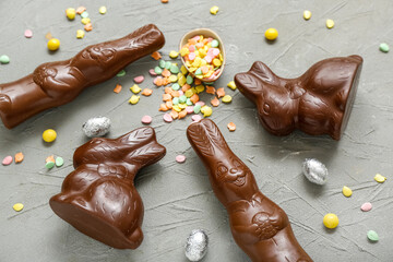 Chocolate Easter egg with sprinkles and bunnies on grey background