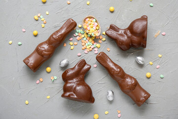 Chocolate Easter egg with sprinkles and bunnies on grey background