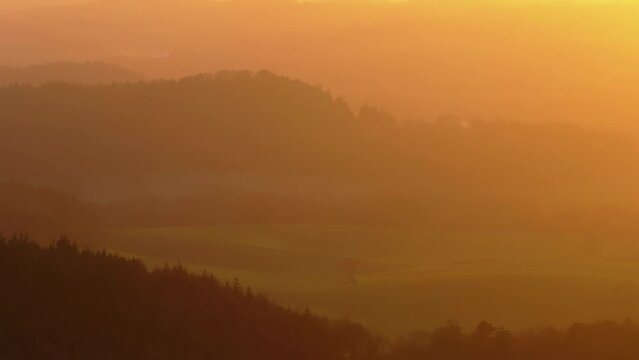 Tracking telephoto shot of rural landscape at sunset golden hour