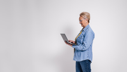 Side view of focused senior professional analyzing business report over laptop on white background