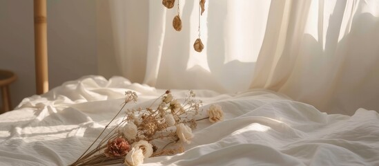 Contrasting cream beige shades adorn a white bed with pendant earrings made of gold and dried roses, leaving space for text.