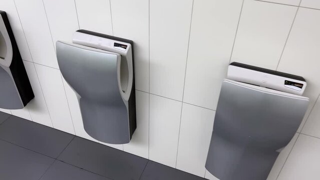 Automatic sensory hand dryers on the wall of a public restroom