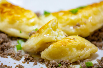 Traditional Ukrainian pierogi grilled in butter and served with minced meat and cream, decorated with fresh fine herbs