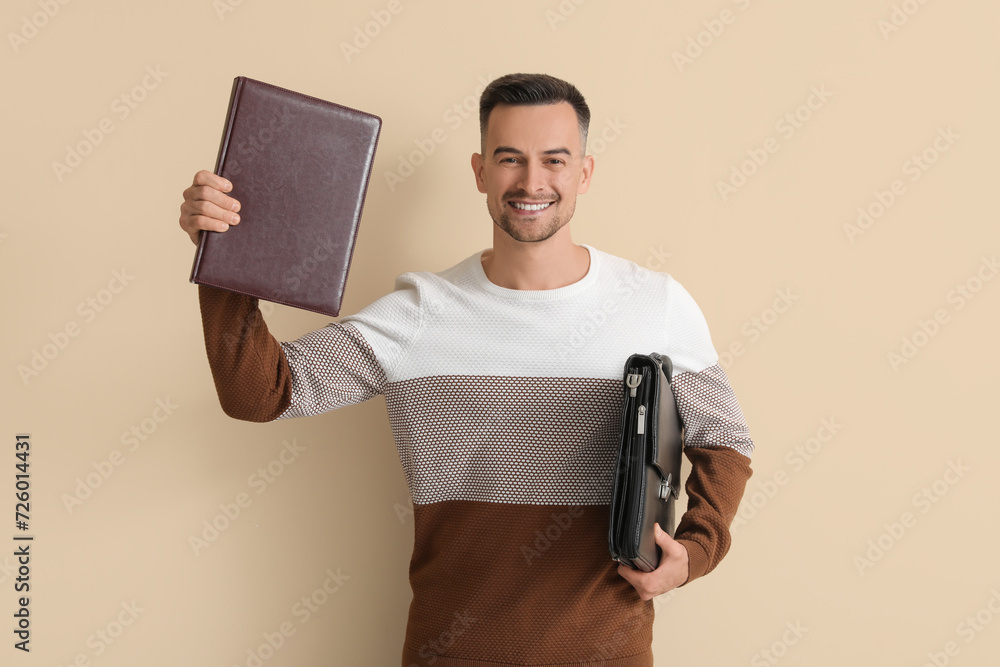 Wall mural happy young man with book and briefcase on beige background