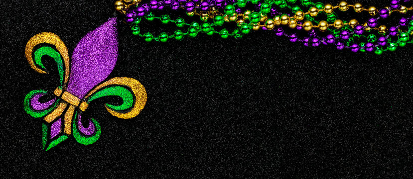 Mardi Gras beads with Fleur de lis, in glittering green, purple, and gold. Sparkling festive background for Mardi Gra in traditional colors.