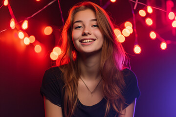 A woman is smiling in front of a string of lights