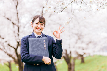 満開の桜の下で卒業証書を持つ高校生・女子高生（卒業生・卒業式・卒業・ok・成功・成果）
 - obrazy, fototapety, plakaty