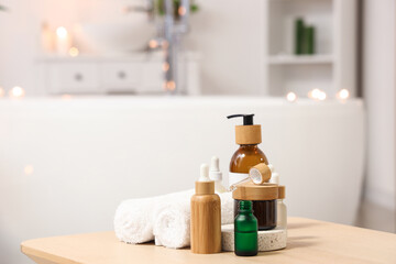 Fototapeta na wymiar Bottles of skincare products with towels on table in bathroom, closeup