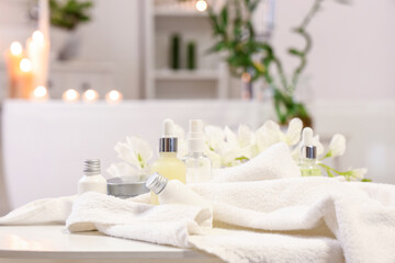 Fototapeta na wymiar Bottles of skincare products with towel on table in bathroom, closeup