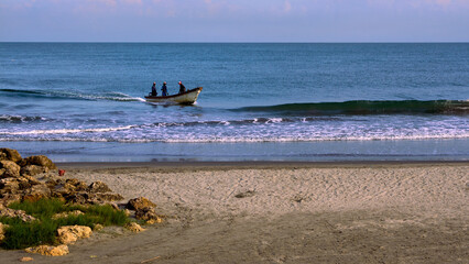 Boat with unrecognisable fishermen approaching the beach in Cartagena Colombia.