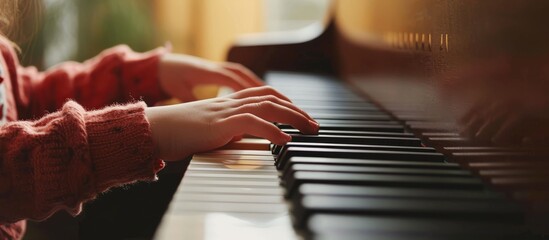 Child's hands playing piano, focused on fingers and keys.