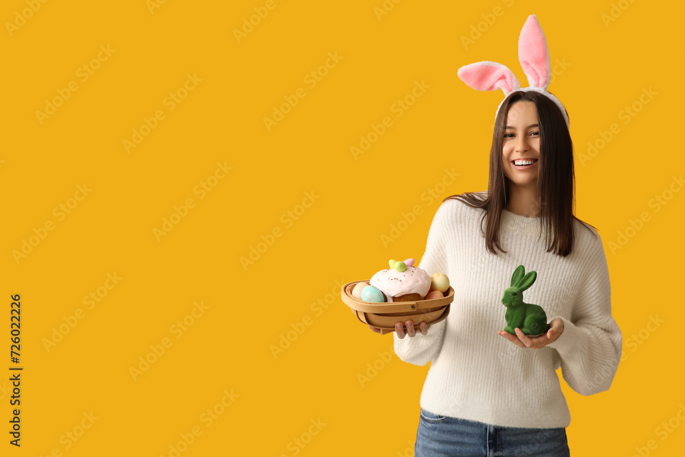 Poster pretty young woman with bunny ears, toy rabbit and easter basket on yellow background