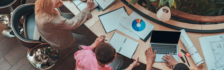 Group of coworkers working together and talking at modern office. Workplace and cooperation concept