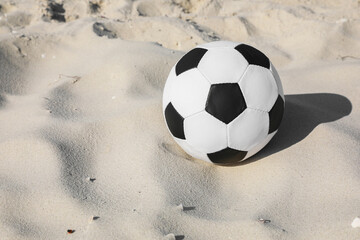 Soccer ball on sand, space for text. Football equipment