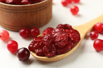 Tasty dried cranberries and fresh ones on white table, closeup