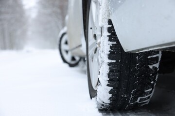 Car with winter tires on snowy road outdoors, closeup. Space for text