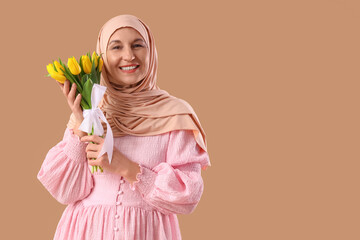 Mature Muslim woman with tulips on brown background. Ramadan celebration