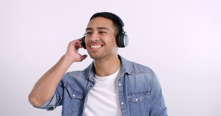Man, headphones and dancing to music in studio, streaming radio and hip hop playlist by pink background. Asian male person, freedom and happy energy for song, mockup space and listening to sound