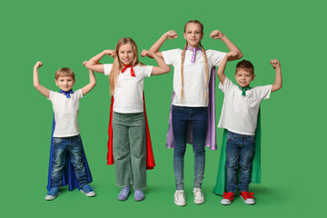 Cute kids dressed as superheroes on green background