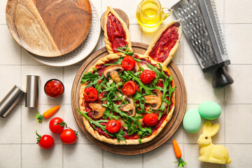 Composition with tasty pizza and painted eggs for Easter celebration on white tile background