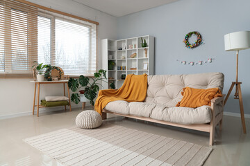 Interior of stylish living room with Easter wreath, shelf unit and sofa