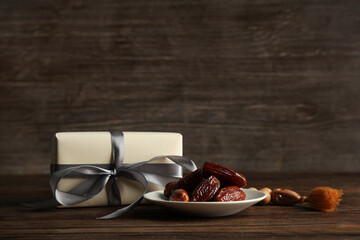 Gift box with dried dates and prayer beads for Ramadan on wooden table
