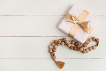 Gift box with prayer beads for Ramadan on white wooden table