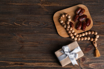 Gift box with dried dates and prayer beads for Ramadan on wooden table