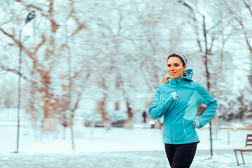 Active Woman Running During Winter in a Park. Cheerful jogger working out during cold days outdoors...
