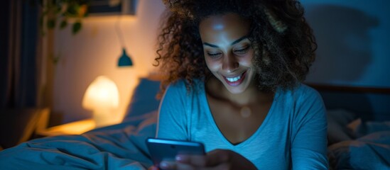 Young woman happily using a touch screen phone in her bedroom.