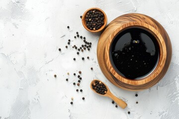 Top view of a wooden bowl with balsamic vinegar and peppercorns on a white textured table room for text
